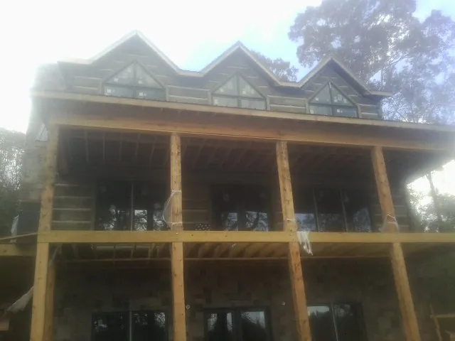 Dormers and porch framing on a large log home under construction — Roof Coating work by our crew in Wright City