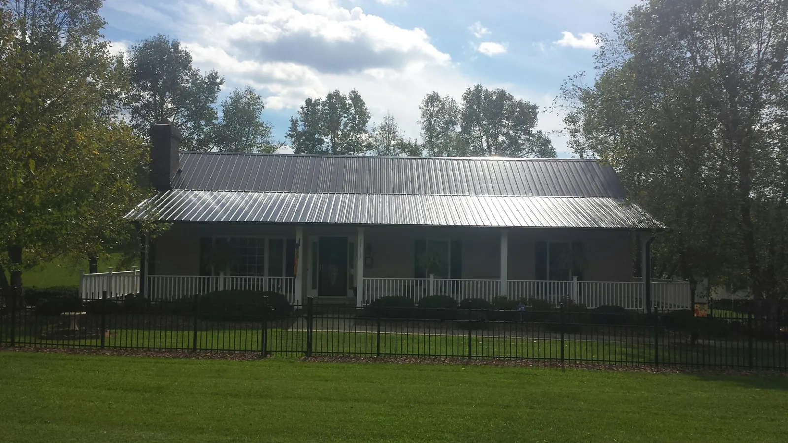 Gray metal roof on a brick ranch with a full width front porch — Gutter Guard Installation work by our crew in Wright City