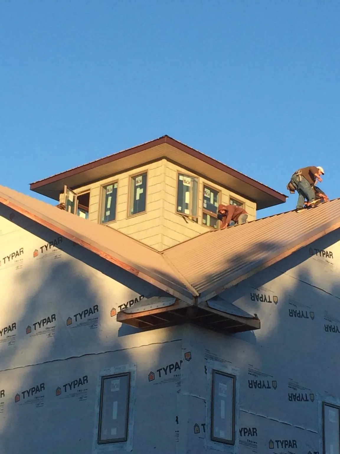 Roofers working around a rooftop cupola on a new metal roof at sunset — Roof Waterproofing in Wright City by Roofing Brothers